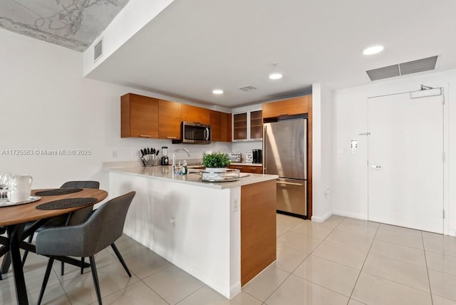 kitchen with sink, stainless steel appliances, light tile patterned flooring, and kitchen peninsula