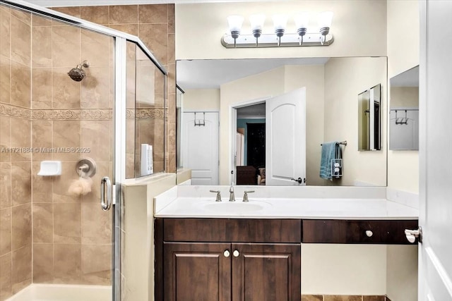 bathroom featuring a shower with door and vanity