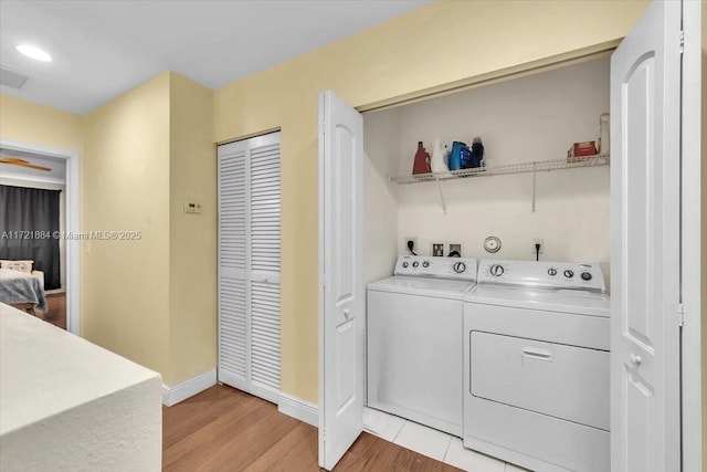 laundry area with washing machine and clothes dryer and light hardwood / wood-style floors