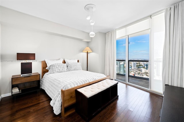 bedroom featuring access to outside, dark wood-type flooring, and a wall of windows