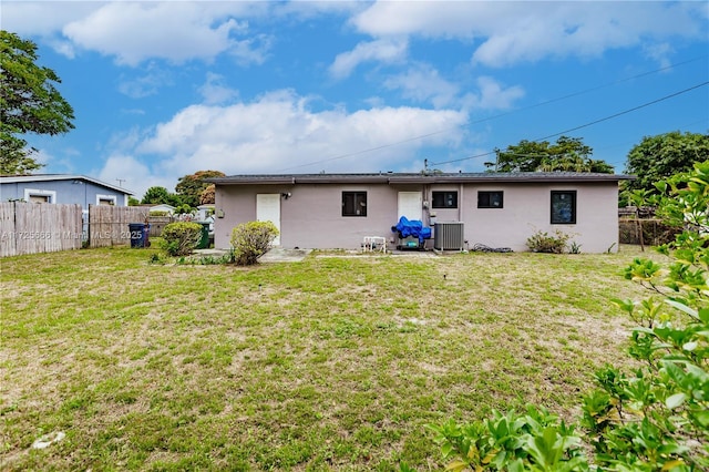 back of house featuring central air condition unit and a lawn