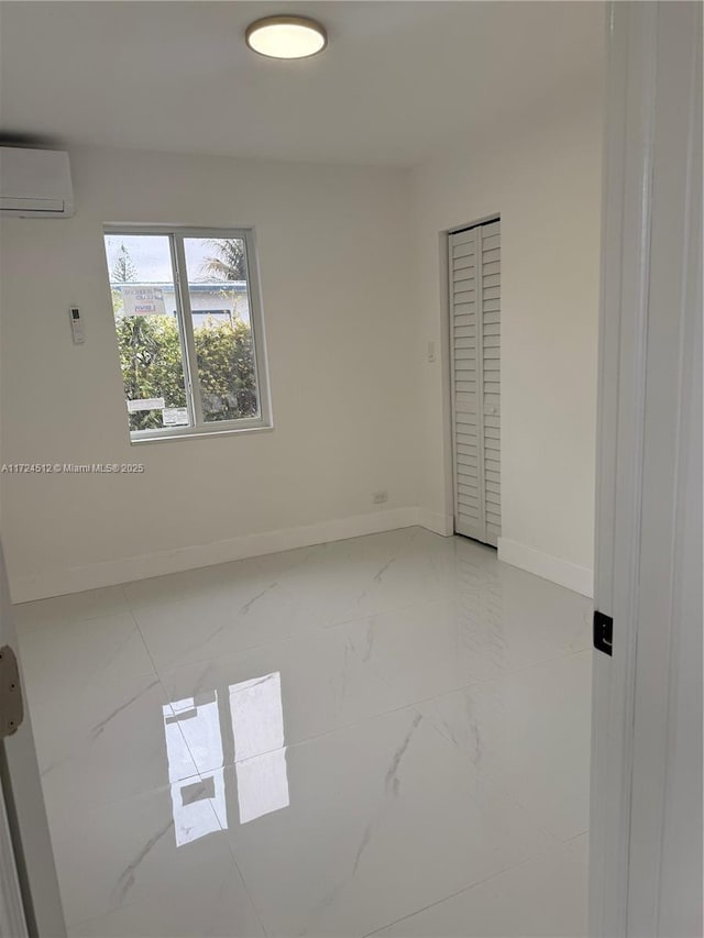 unfurnished bedroom featuring an AC wall unit and a closet