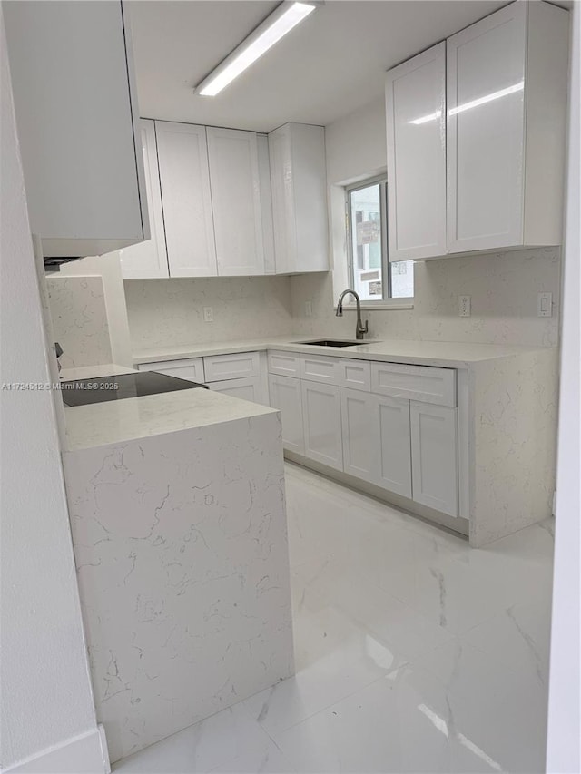 kitchen featuring sink, black electric cooktop, and white cabinetry