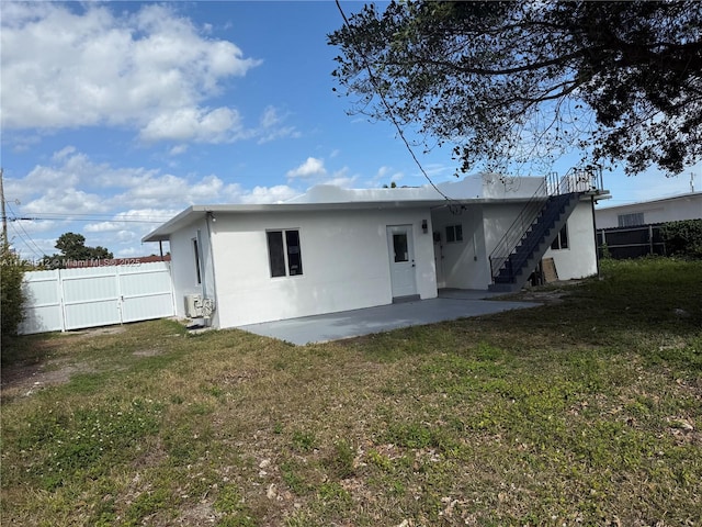 rear view of property featuring a lawn and a patio area