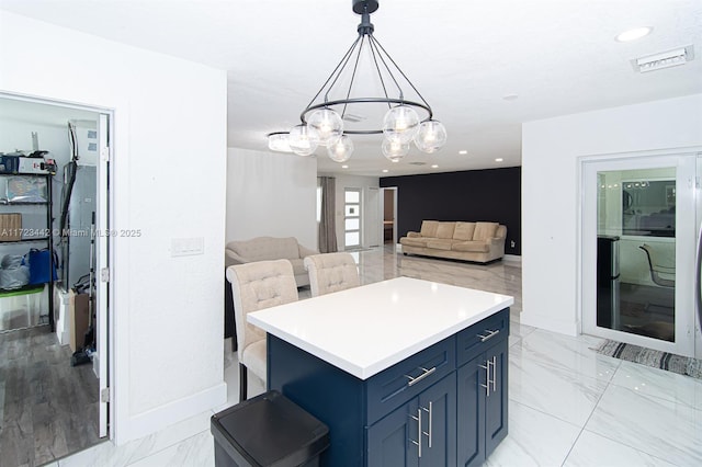 kitchen with blue cabinets, a center island, a breakfast bar area, hanging light fixtures, and a chandelier