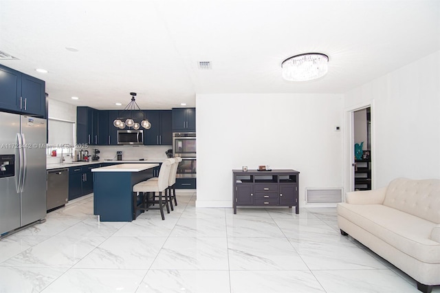 kitchen with appliances with stainless steel finishes, blue cabinets, a kitchen bar, and a kitchen island