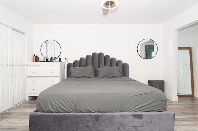 bedroom featuring light hardwood / wood-style floors, ceiling fan, and a closet