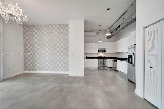 kitchen with pendant lighting, white cabinetry, concrete floors, and appliances with stainless steel finishes