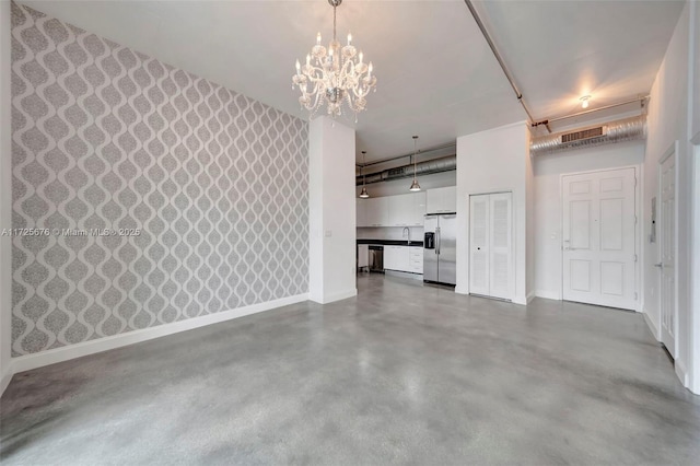 unfurnished living room featuring concrete floors and an inviting chandelier