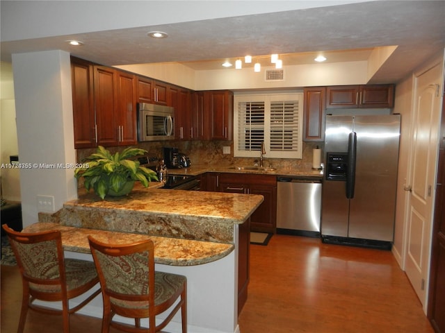 kitchen featuring a kitchen breakfast bar, stainless steel appliances, kitchen peninsula, and sink