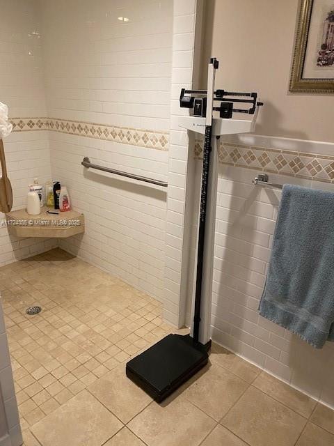 bathroom with tile patterned flooring, tile walls, and walk in shower