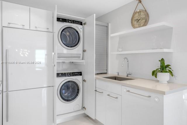 clothes washing area with laundry area, a sink, and stacked washing maching and dryer