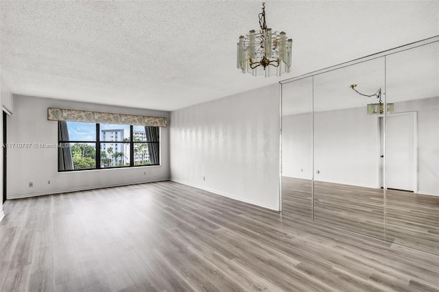 unfurnished living room with a textured ceiling, hardwood / wood-style floors, and a notable chandelier