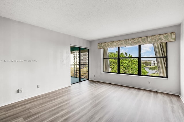 unfurnished room featuring a textured ceiling and light hardwood / wood-style flooring