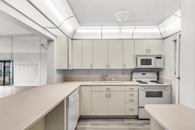 kitchen with sink, white appliances, light hardwood / wood-style floors, and cream cabinetry