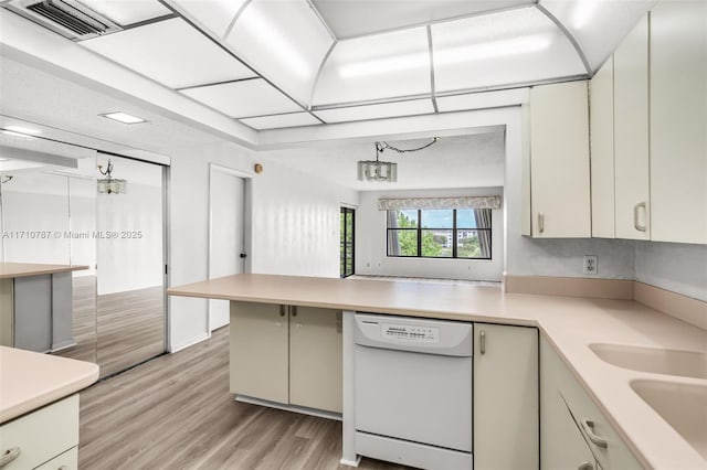 kitchen with sink, white dishwasher, light wood-type flooring, and kitchen peninsula