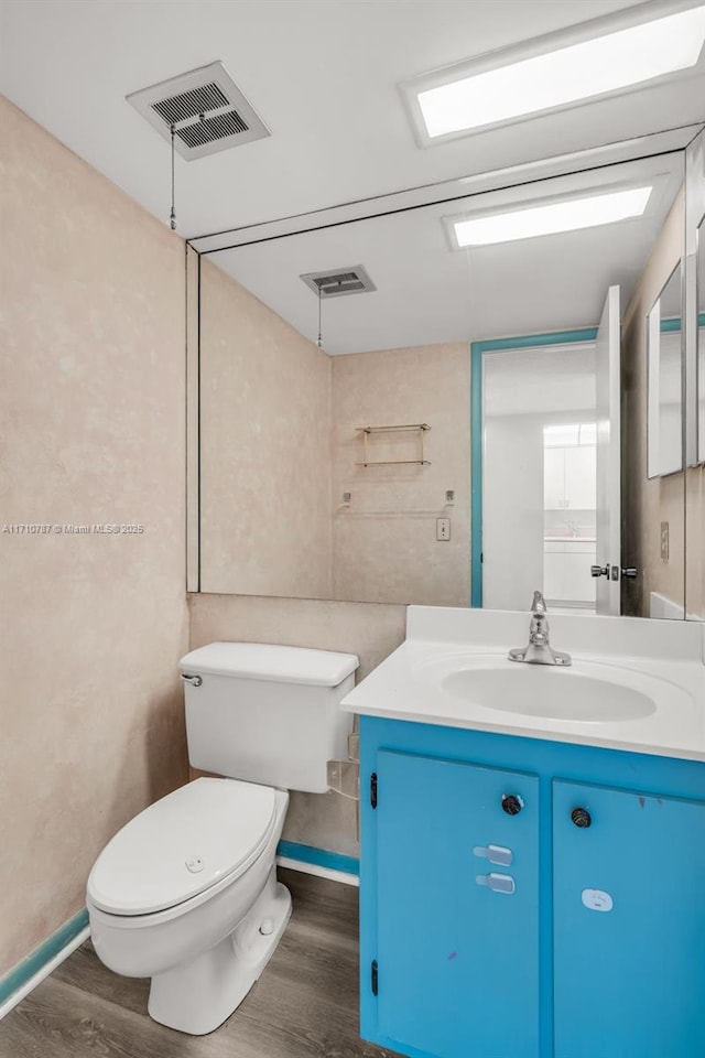 bathroom with toilet, vanity, and hardwood / wood-style floors