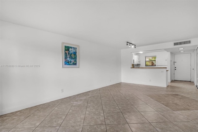 unfurnished living room featuring track lighting and light tile patterned floors