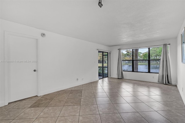 tiled spare room with a textured ceiling and a water view