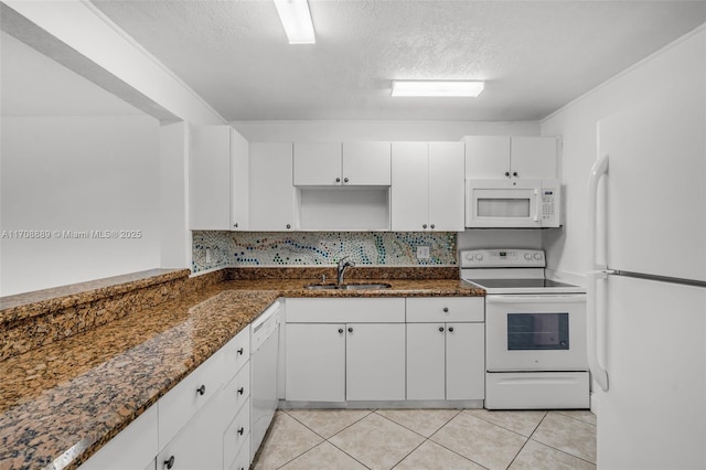 kitchen with white appliances, a textured ceiling, white cabinetry, dark stone countertops, and sink