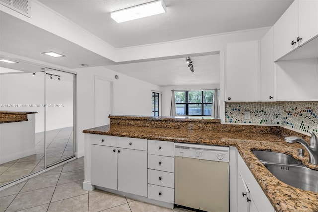 kitchen with white dishwasher, white cabinets, dark stone counters, and sink