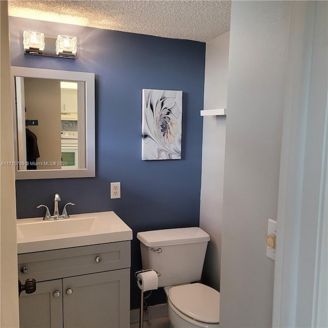 bathroom featuring toilet, a textured ceiling, and vanity