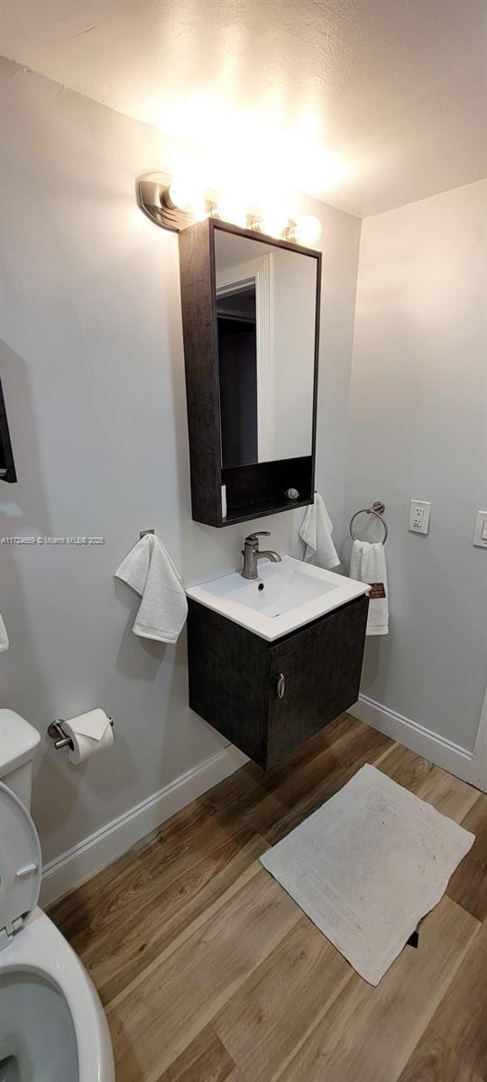 bathroom with toilet, hardwood / wood-style flooring, and vanity