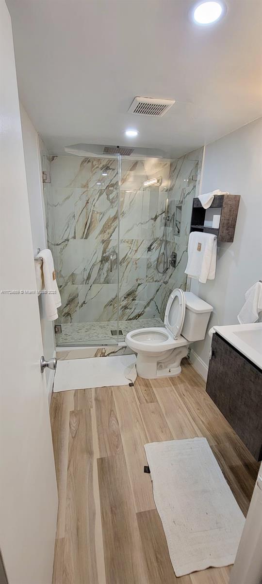 bathroom featuring tiled shower, vanity, and toilet