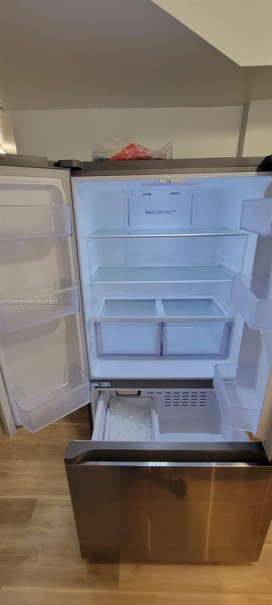 interior details featuring fridge and wood-type flooring