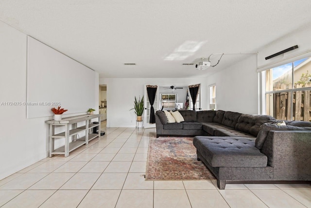 living room with ceiling fan, light tile patterned flooring, and a textured ceiling