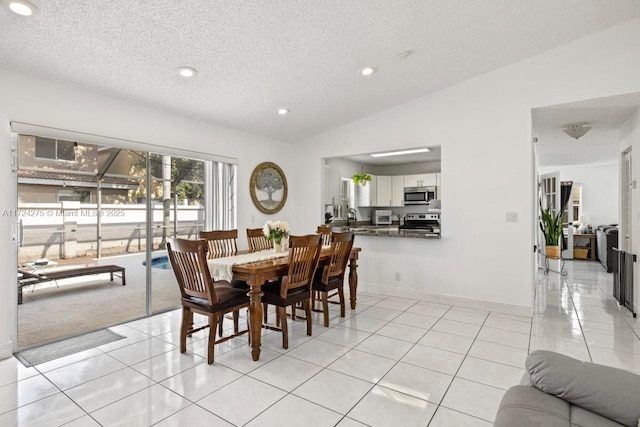 dining area with a textured ceiling, lofted ceiling, sink, and light tile patterned floors