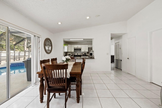 dining space with a textured ceiling, vaulted ceiling, and light tile patterned floors