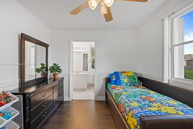 bedroom with a textured ceiling, dark hardwood / wood-style floors, connected bathroom, ceiling fan, and sink