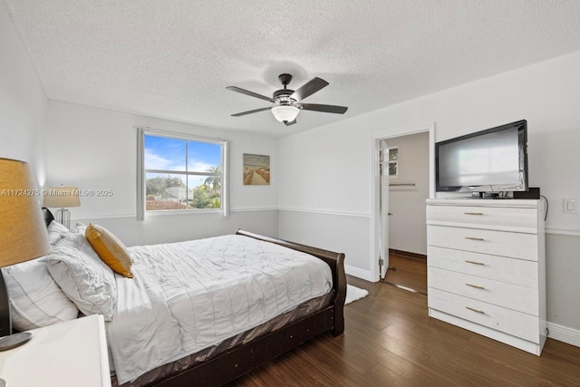 bedroom featuring ceiling fan, dark wood-type flooring, and a textured ceiling