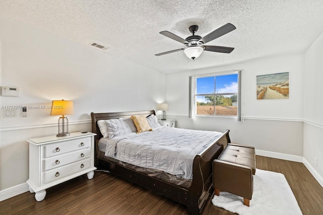 bedroom with a textured ceiling, ceiling fan, and dark wood-type flooring