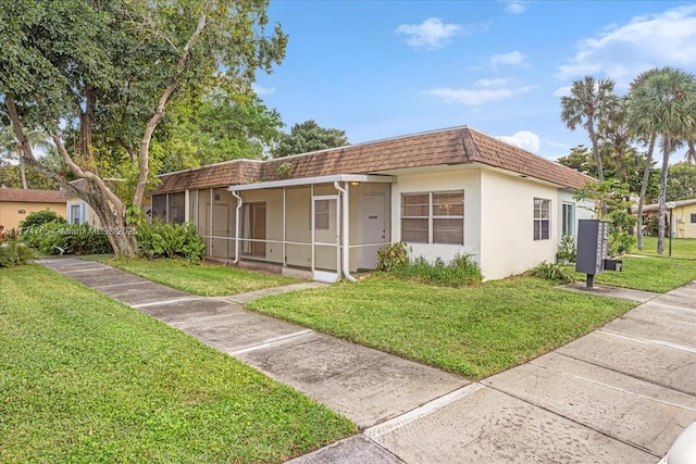 view of front of home with a sunroom and a front lawn