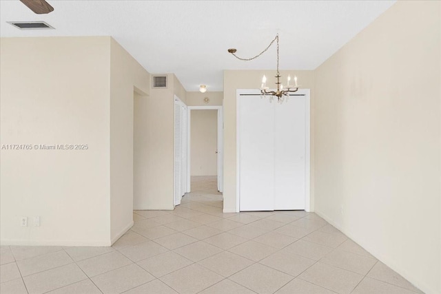 tiled empty room featuring a notable chandelier