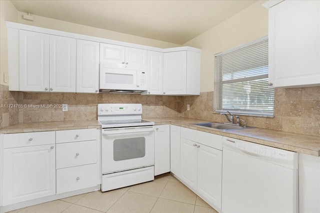 kitchen featuring white appliances, light tile patterned floors, decorative backsplash, white cabinetry, and sink