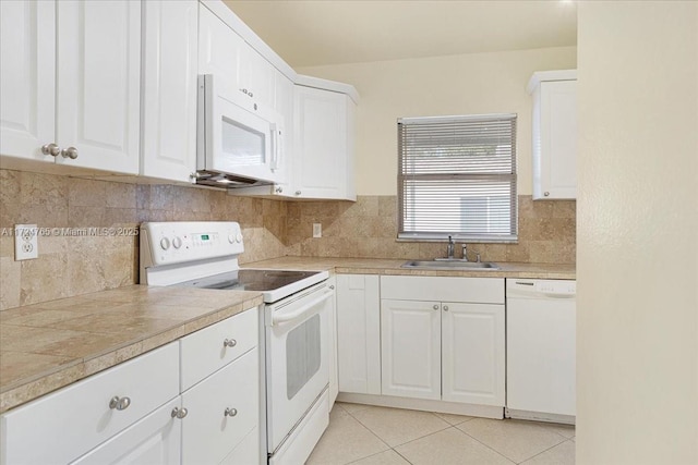 kitchen featuring white appliances, light tile patterned floors, tasteful backsplash, white cabinets, and sink