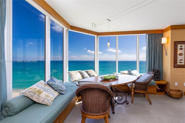 sunroom featuring rail lighting and a water view