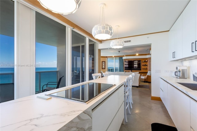 kitchen with light stone countertops, pendant lighting, black electric cooktop, a breakfast bar area, and white cabinetry