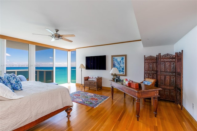 bedroom featuring ceiling fan, access to outside, expansive windows, and hardwood / wood-style flooring