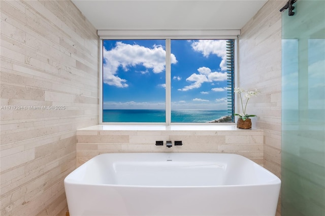 bathroom featuring a tub, wood walls, and a water view