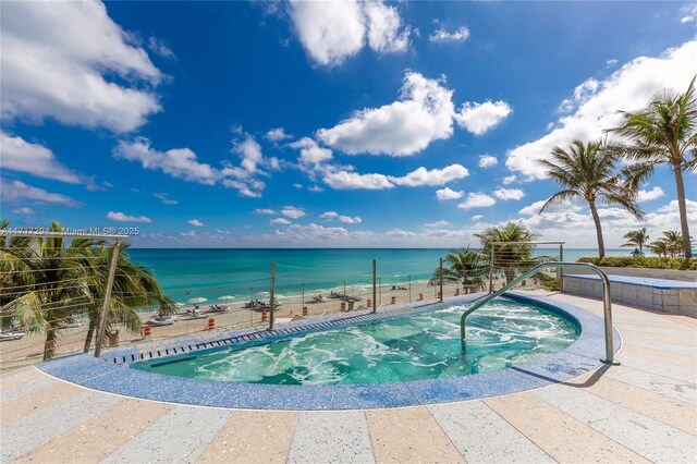 view of swimming pool featuring a hot tub and a water view