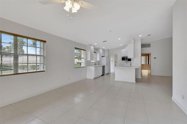 unfurnished living room with ceiling fan, sink, light tile patterned floors, and lofted ceiling