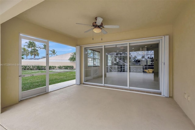 unfurnished sunroom featuring ceiling fan and a wealth of natural light