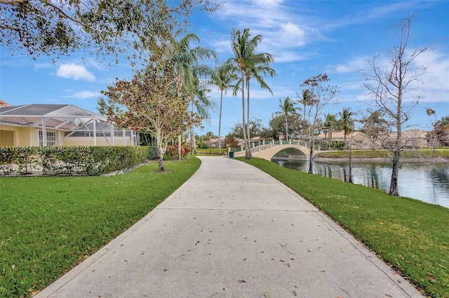 view of property's community with a water view and a lawn