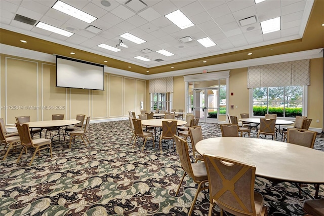 carpeted dining area with a raised ceiling, french doors, and ornamental molding