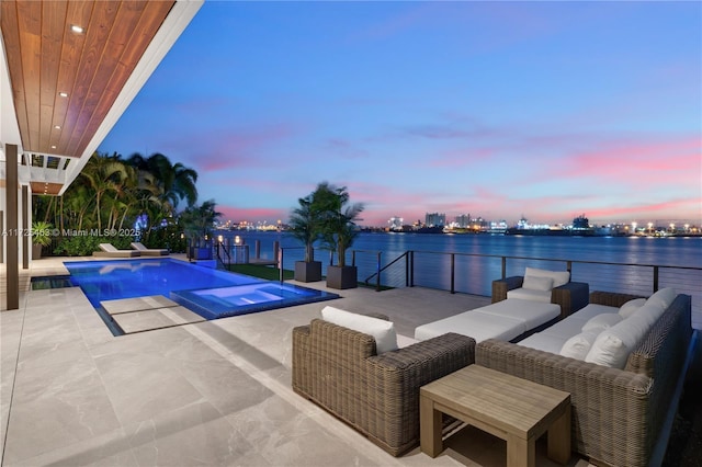 pool at dusk featuring an outdoor living space, a jacuzzi, a patio, and a water view