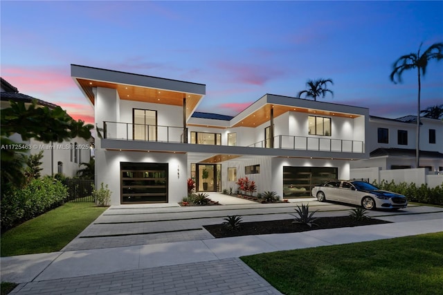 contemporary house with a balcony, a garage, and a lawn